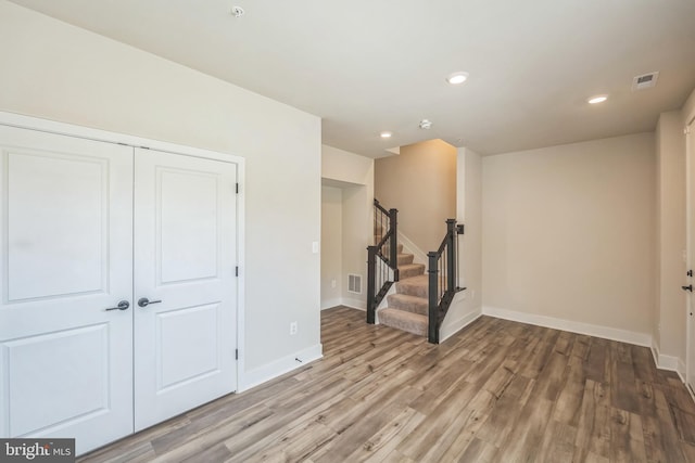 interior space featuring stairway, baseboards, wood finished floors, and visible vents