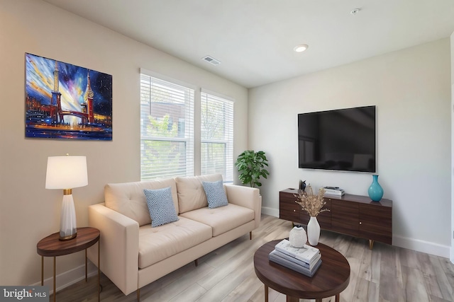 living room with visible vents, baseboards, and wood finished floors