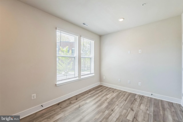 unfurnished room with baseboards, visible vents, and wood finished floors