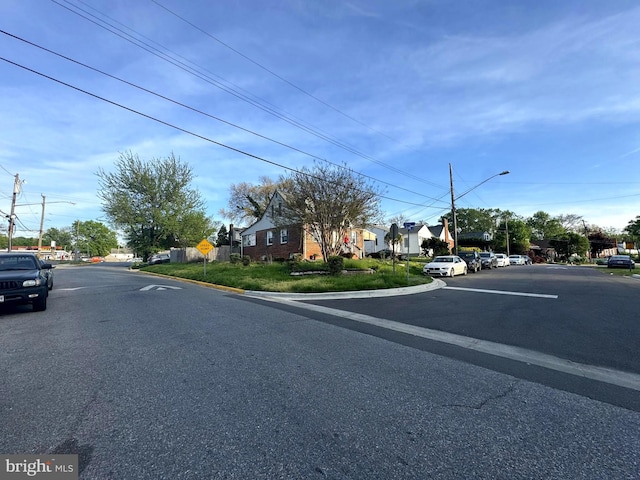 view of street with curbs, street lighting, a residential view, and traffic signs