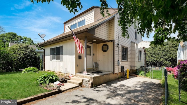 view of front of property featuring fence, a shingled roof, and a front lawn