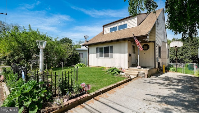 bungalow featuring a front yard, fence, roof with shingles, and aphalt driveway