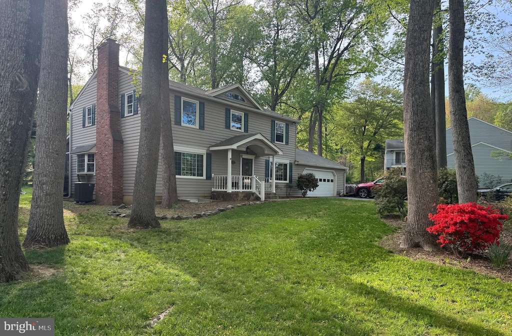 colonial-style house featuring central AC unit, a chimney, and a front lawn
