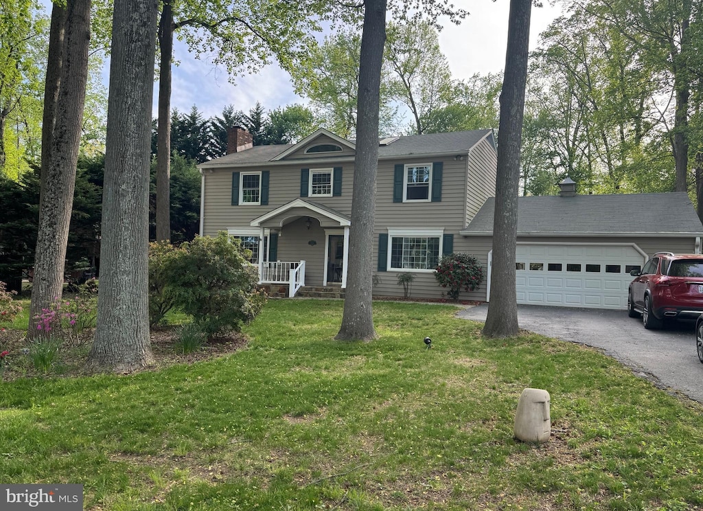 view of front facade with an attached garage, driveway, a chimney, and a front lawn