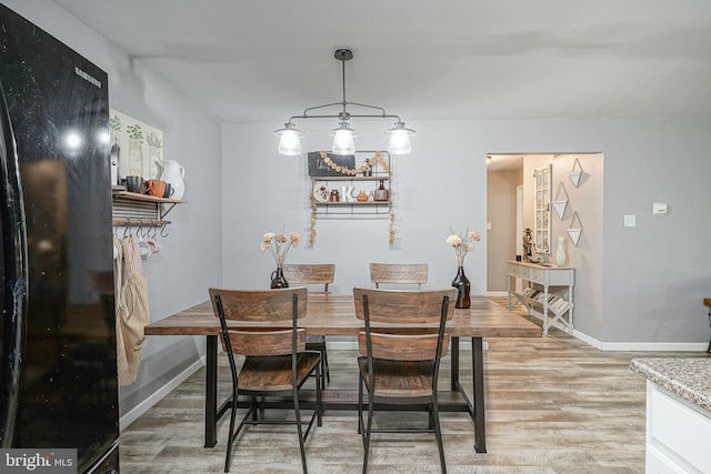 dining space featuring light wood-type flooring and baseboards