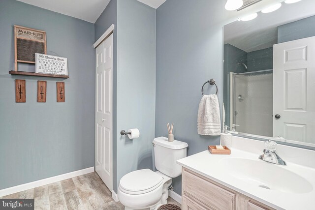 bathroom with vanity, toilet, baseboards, walk in shower, and wood finished floors