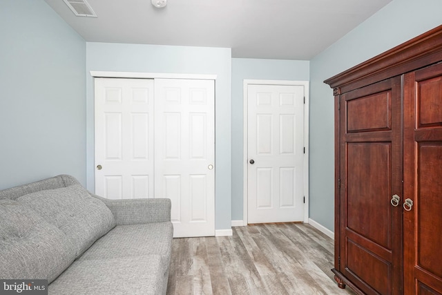 living area with light wood finished floors, visible vents, and baseboards