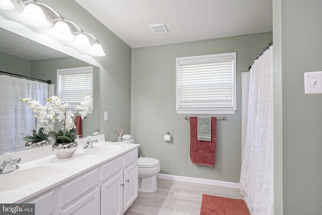full bath featuring toilet, a sink, wood finished floors, and visible vents