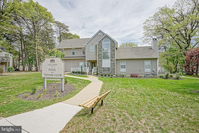 view of front of house with a front lawn, stone siding, and a chimney