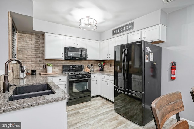 kitchen featuring black appliances, a sink, white cabinets, and tasteful backsplash