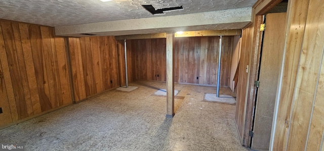 finished basement with a textured ceiling and wood walls