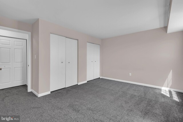 6703 Rapid Water Way Unit 203, Glen Burnie, MD 21060 - unfurnished bedroom with two closets, baseboards, and dark colored carpet
