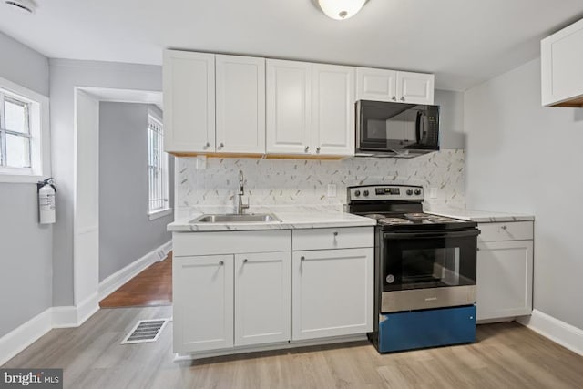 kitchen featuring a healthy amount of sunlight, visible vents, black microwave, stainless steel range with electric cooktop, and a sink