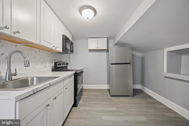 kitchen featuring white cabinets, black microwave, a sink, range with electric cooktop, and freestanding refrigerator