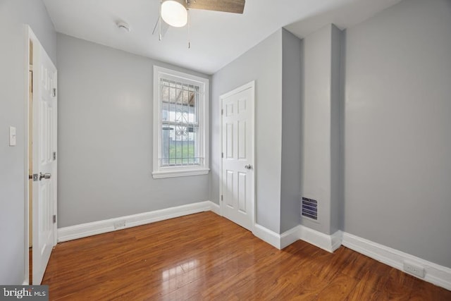unfurnished bedroom with baseboards, ceiling fan, wood finished floors, and visible vents
