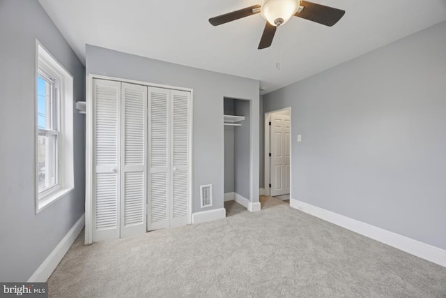 unfurnished bedroom featuring carpet floors, multiple windows, and visible vents