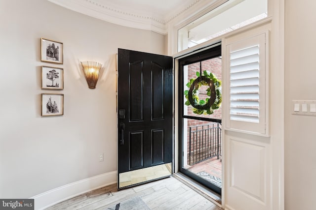 foyer featuring wood finished floors, baseboards, and ornamental molding