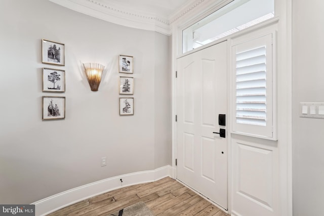 foyer entrance with light wood finished floors, baseboards, and crown molding