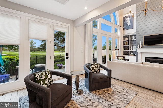 living room featuring wood-type flooring, a glass covered fireplace, built in features, and recessed lighting