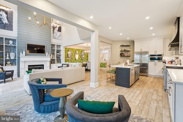 kitchen featuring high end appliances, a chandelier, light countertops, light wood-type flooring, and a breakfast bar area