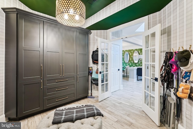 spacious closet featuring french doors, a chandelier, and light wood-style floors