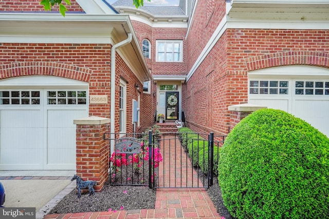 doorway to property with brick siding, a gate, fence, an attached garage, and driveway