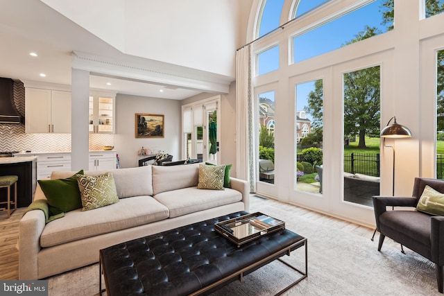 living area featuring light wood finished floors, recessed lighting, and a high ceiling