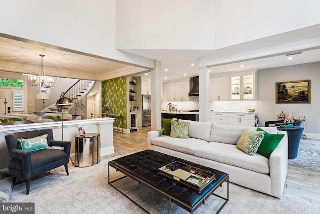 living room with light wood finished floors, a chandelier, recessed lighting, baseboards, and crown molding