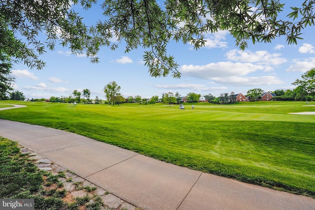view of home's community featuring view of golf course and a yard