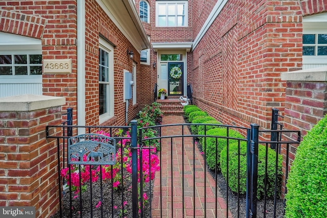 view of exterior entry featuring a gate, brick siding, and fence