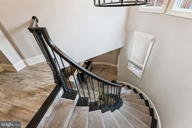 stairs featuring baseboards, wood finished floors, and a chandelier