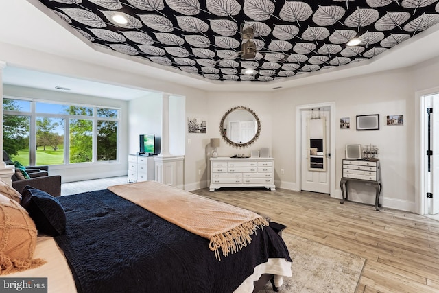 bedroom featuring light wood finished floors, baseboards, and ornate columns