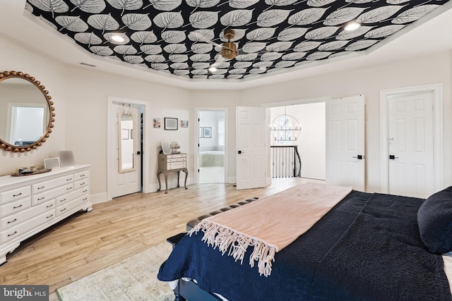 bedroom with light wood-type flooring, baseboards, ensuite bathroom, and a chandelier