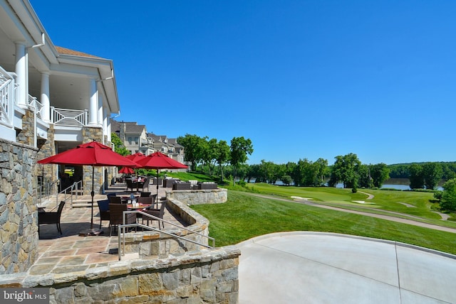 view of grassy yard featuring a patio, golf course view, and a balcony