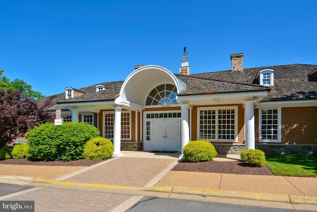 view of front of house with stone siding and a chimney