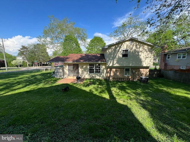 rear view of house with a lawn, cooling unit, and a fenced backyard