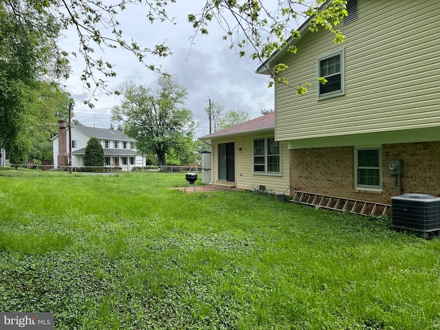 view of yard featuring central AC and fence