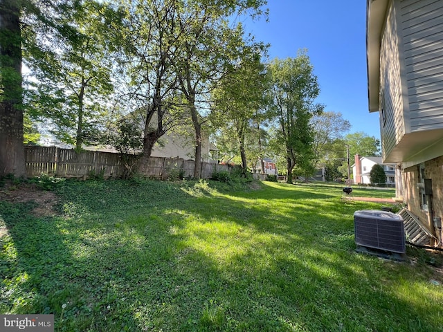 view of yard featuring fence and central AC