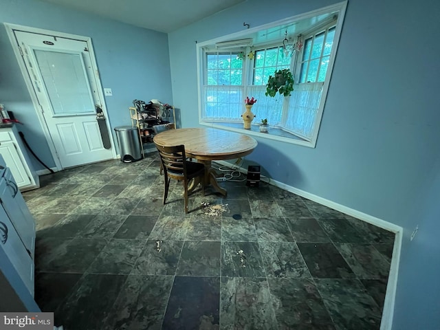 dining space with baseboards and stone finish floor