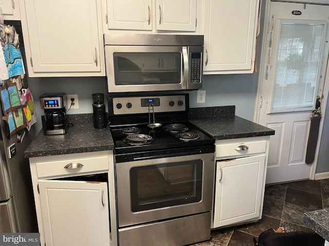 kitchen with white cabinets, stainless steel appliances, and stone finish flooring