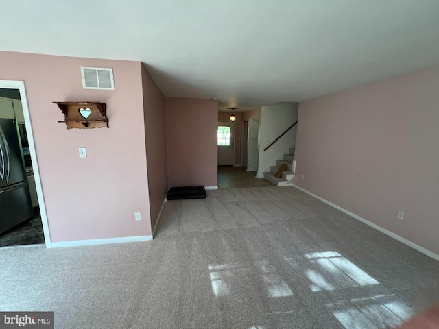 unfurnished living room featuring stairway, carpet, baseboards, and visible vents