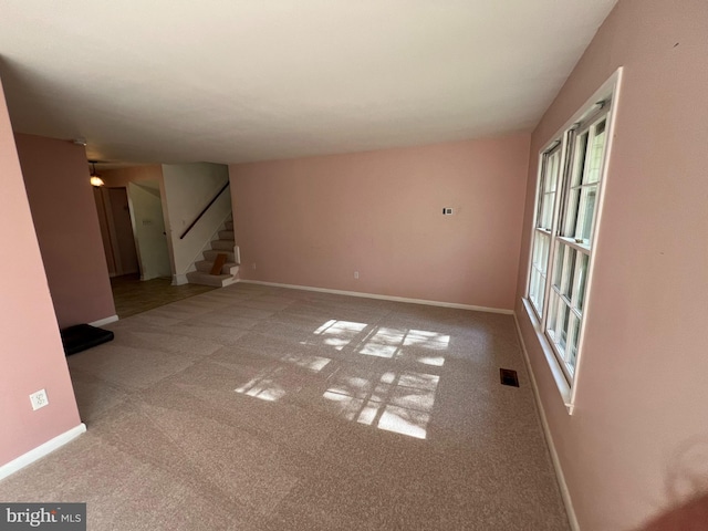 unfurnished living room with carpet flooring, stairway, baseboards, and visible vents