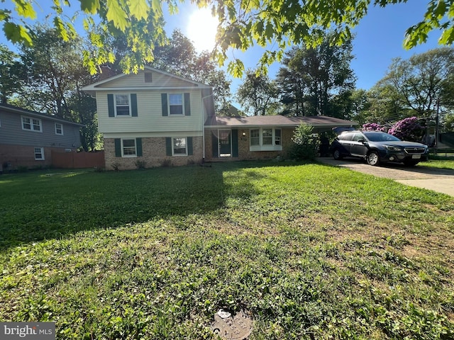 tri-level home with a chimney, fence, a front lawn, brick siding, and driveway
