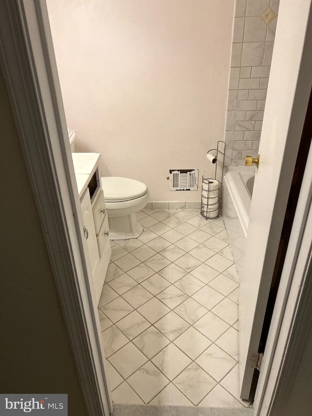 full bath featuring toilet, marble finish floor, vanity, a tub, and a shower