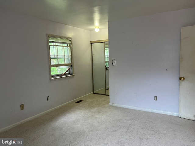 spare room with carpet, baseboards, and visible vents