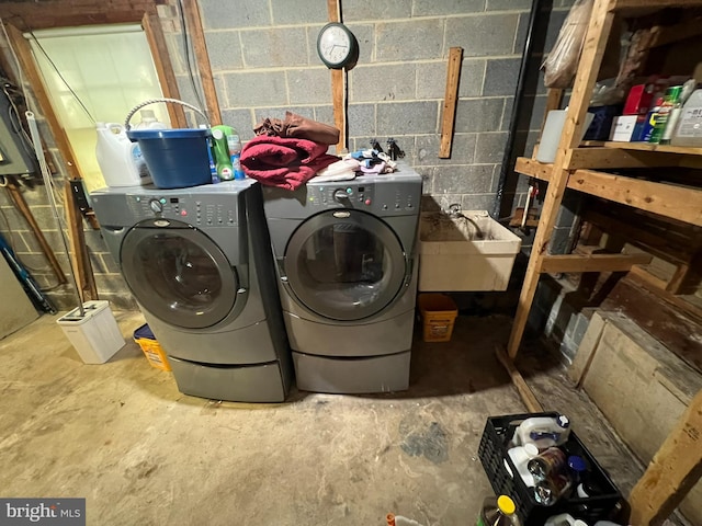 laundry area with washing machine and clothes dryer, concrete block wall, and a sink