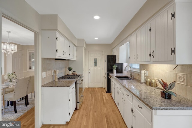 4303 S Valiant Ct, Annandale, VA 22003 - kitchen with stainless steel gas range oven, a sink, light wood-type flooring, white cabinets, and backsplash