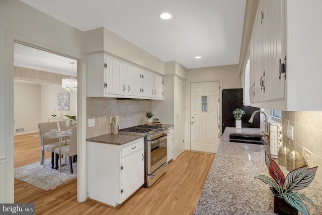 4303 S Valiant Ct, Annandale, VA 22003 - kitchen with gas stove, a sink, tasteful backsplash, white cabinetry, and light wood-type flooring