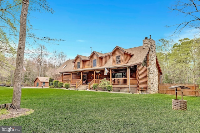 view of front of home with fence, a chimney, a front yard, and log exterior