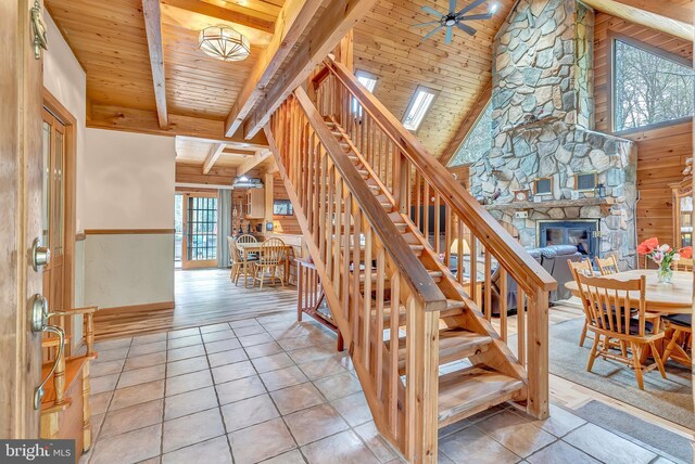stairs featuring wooden ceiling, vaulted ceiling with beams, tile patterned floors, and a fireplace